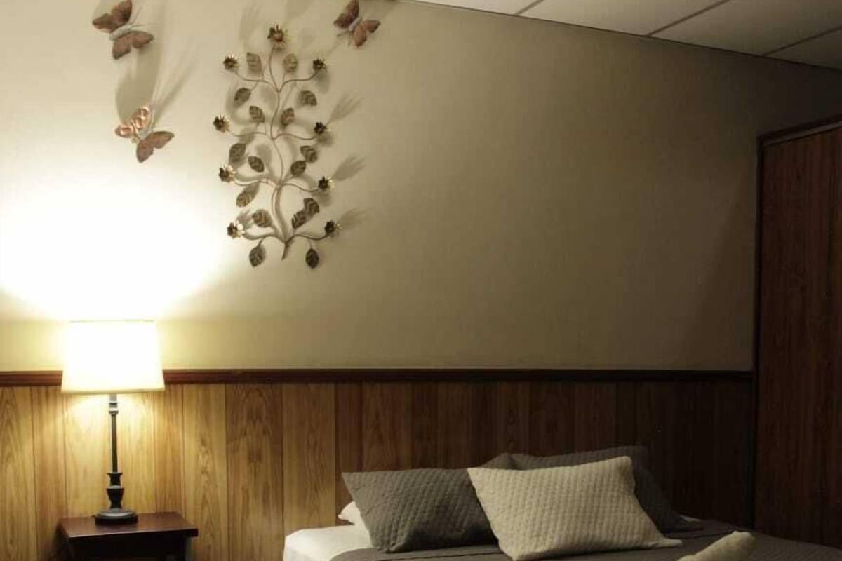 Ein Hotelzimmer mit Bett, Nachttisch, Lampe und Wandbild.