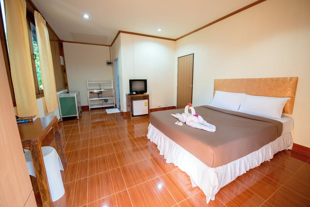 A hotel room with a large bed, a television, a desk, and a chair.