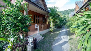A wooden house with a porch and steps leading to a door, surrounded by lush greenery and a clear sky. - Poonsap Resort (Ko Lanta)