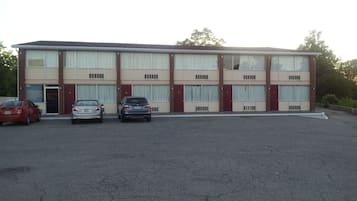 A motel with a two-story structure, a parking lot, and three parked cars.