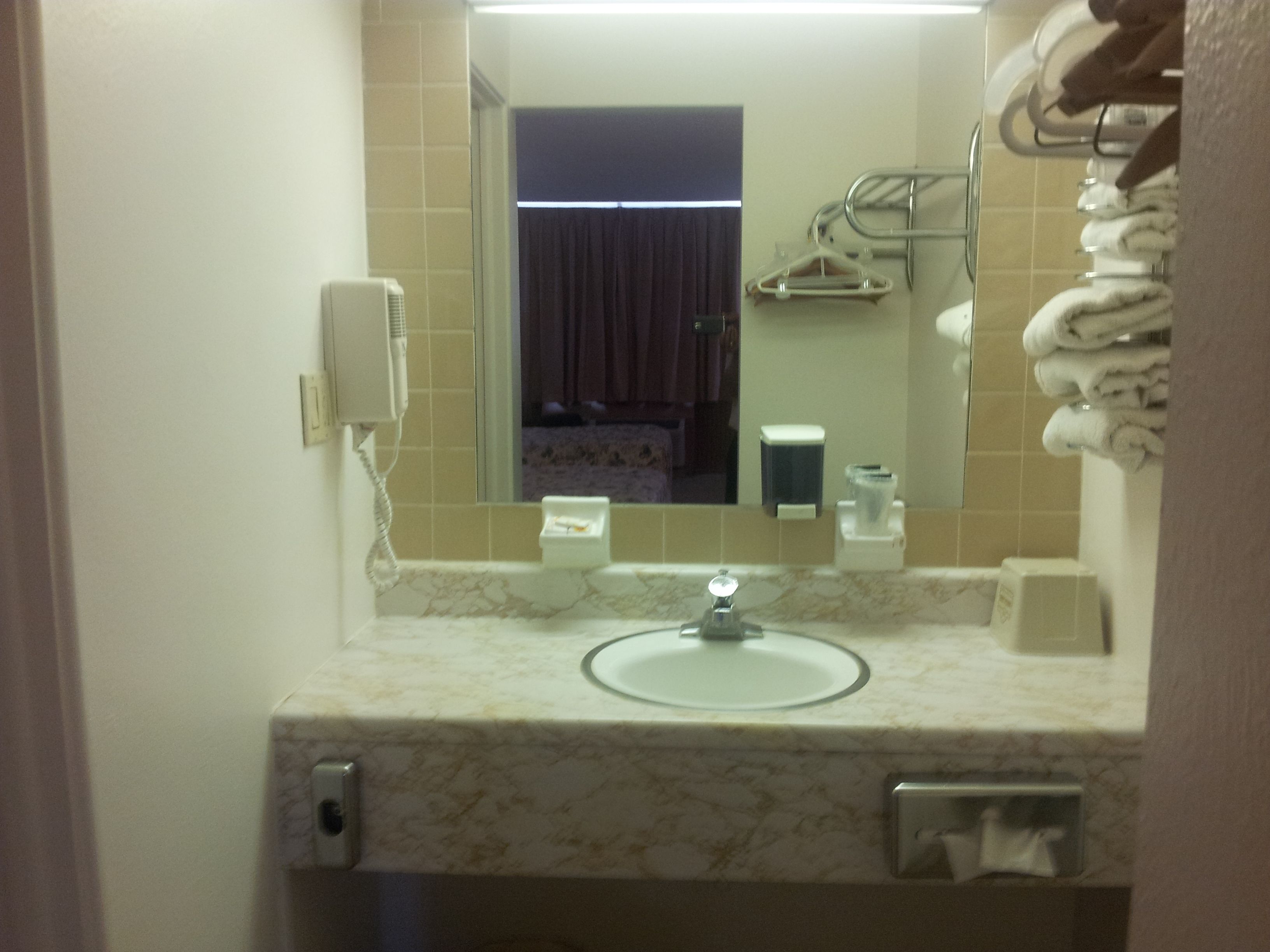 A bathroom with a sink, mirror, towel rack, and a telephone.