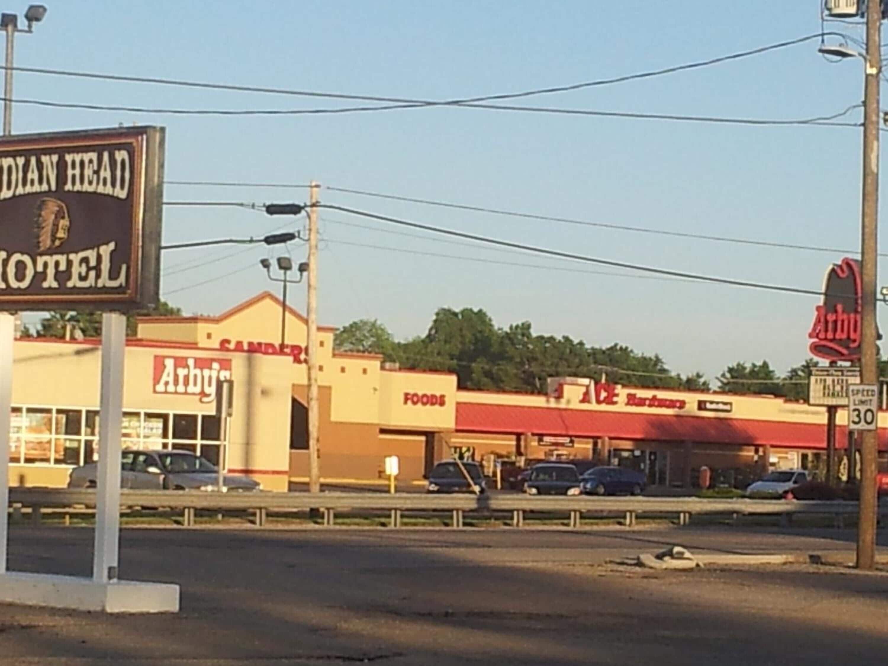 A hotel named 'Indian Head' with a signboard, a fast-food restaurant 'Arby's' in the background, and a speed limit sign of 30.
