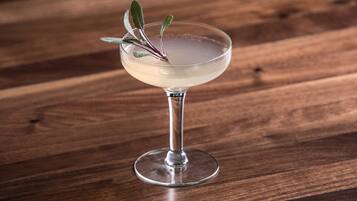 A cocktail in a stemmed glass with a garnish on a wooden surface.
