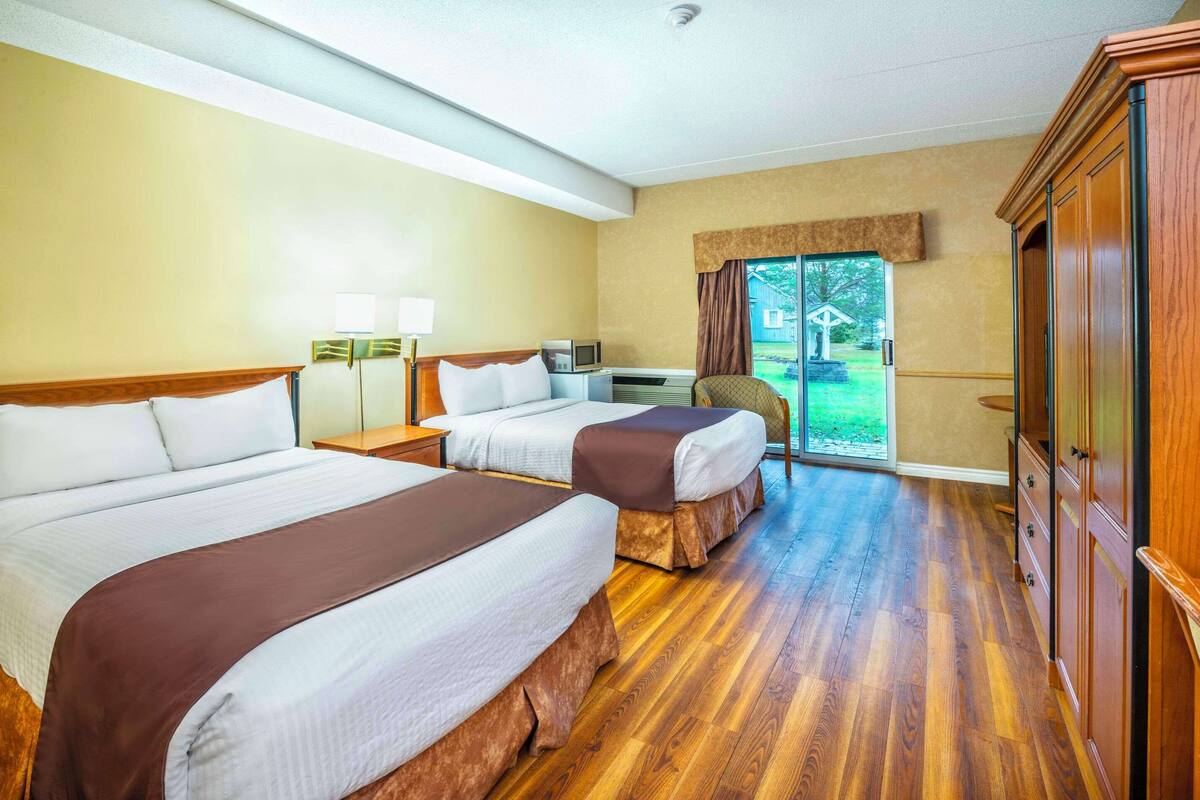 A hotel room with two beds, a desk, a chair, a television, and a wardrobe.