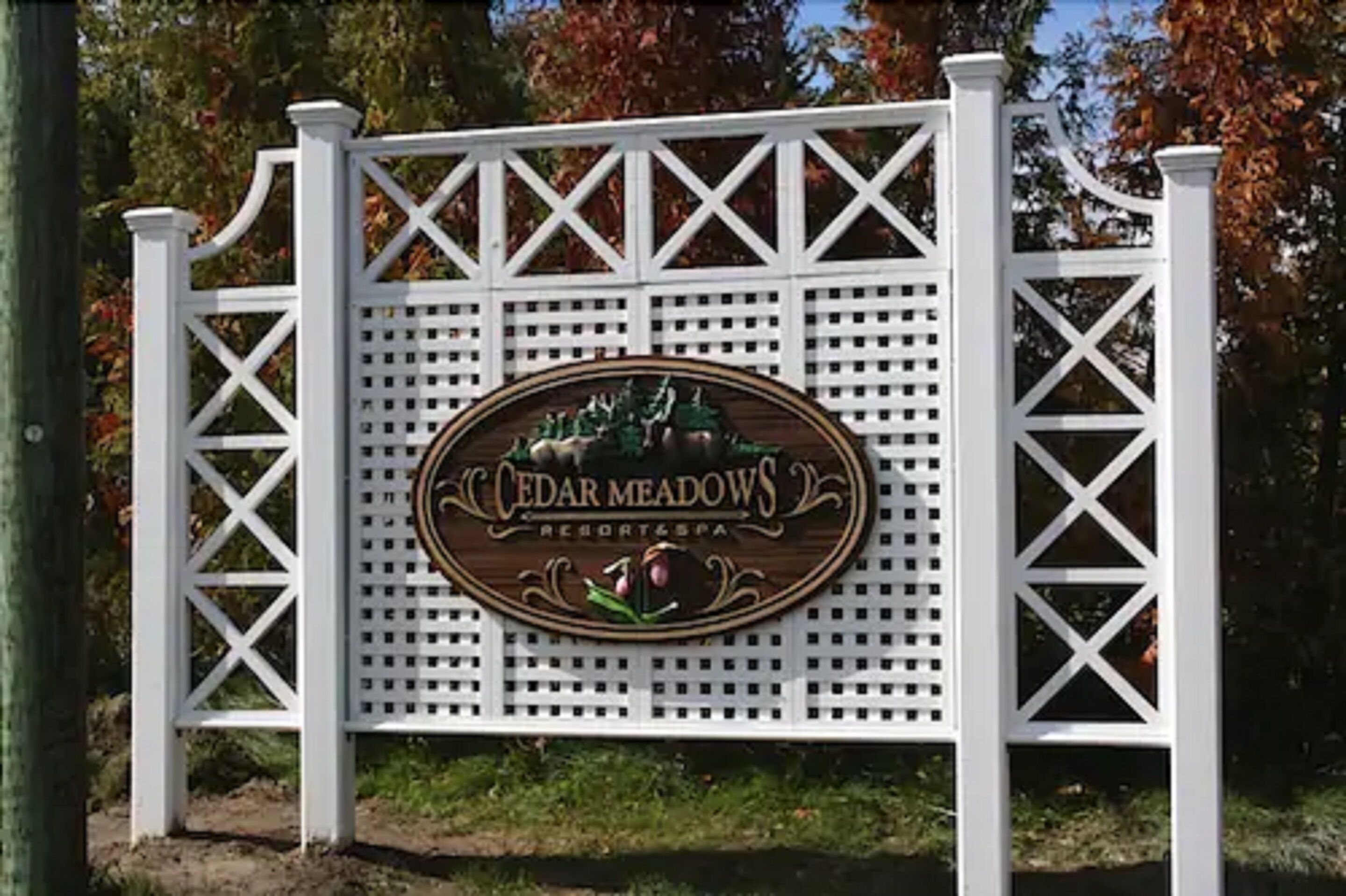A white wooden sign with the text "Cedar Meadows Resort & Spa" and a logo.