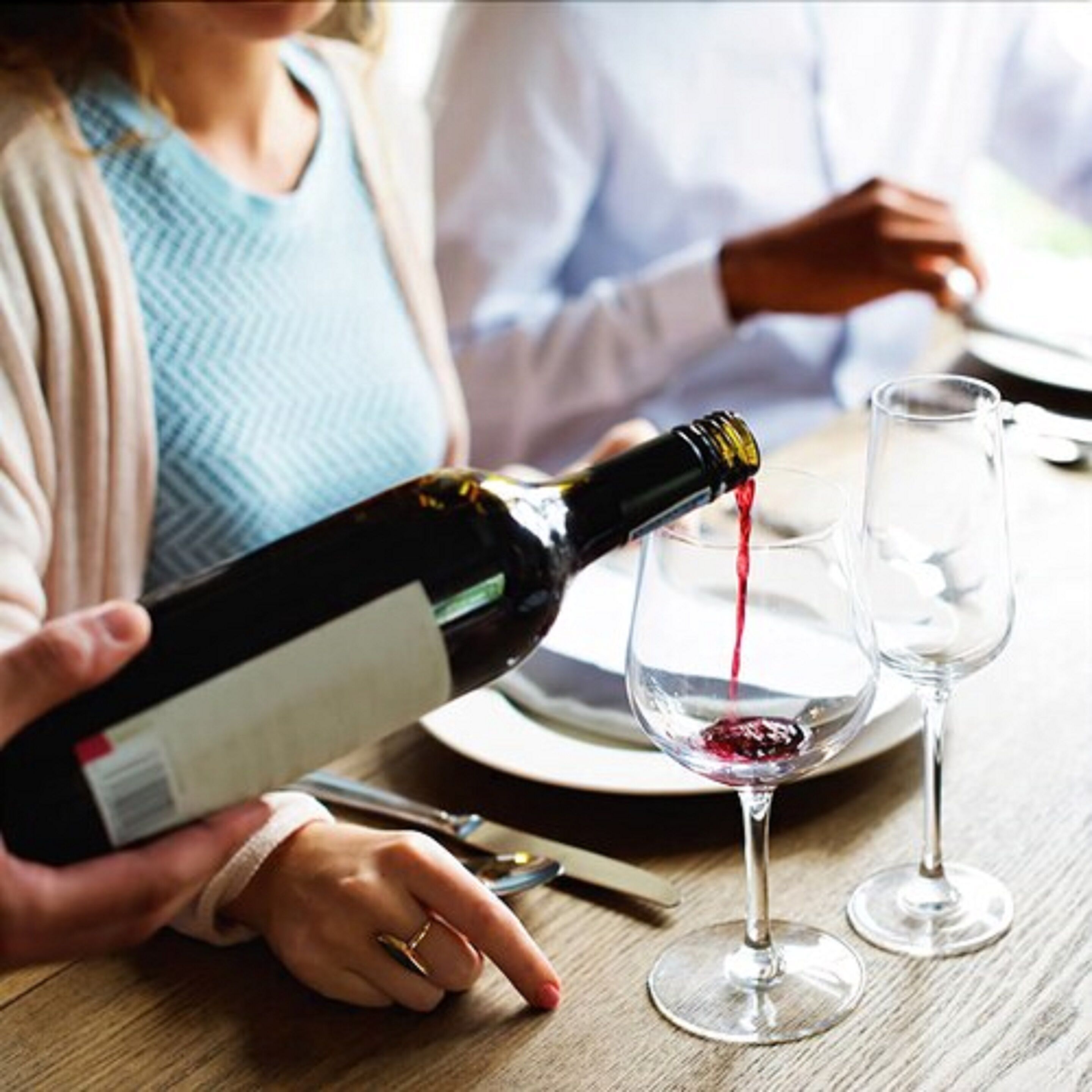 Eine Person gießt Wein in ein Glas.