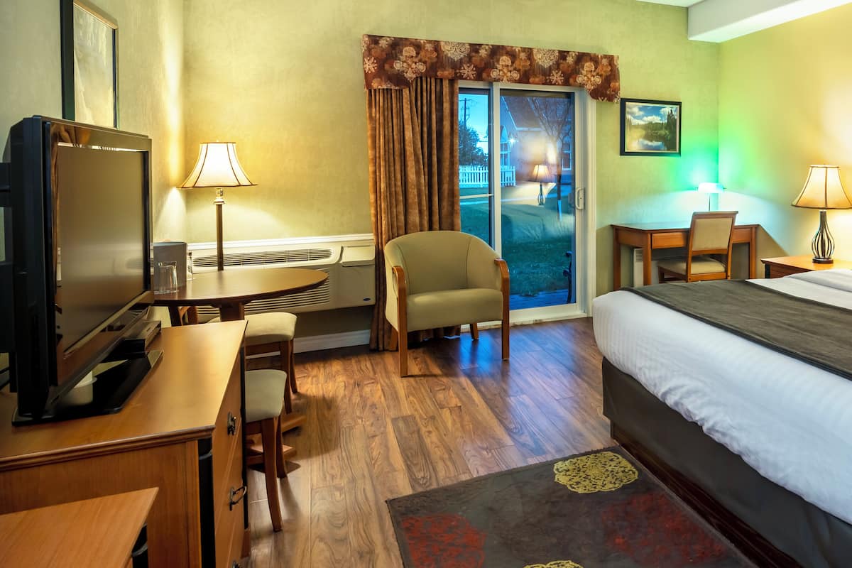 A hotel room with a bed, desk, chair, television, and a view of the outdoors.