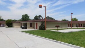 A motel with a single-story structure, a parking lot, and a well-maintained lawn. - Bayshore Motel (La Porte)