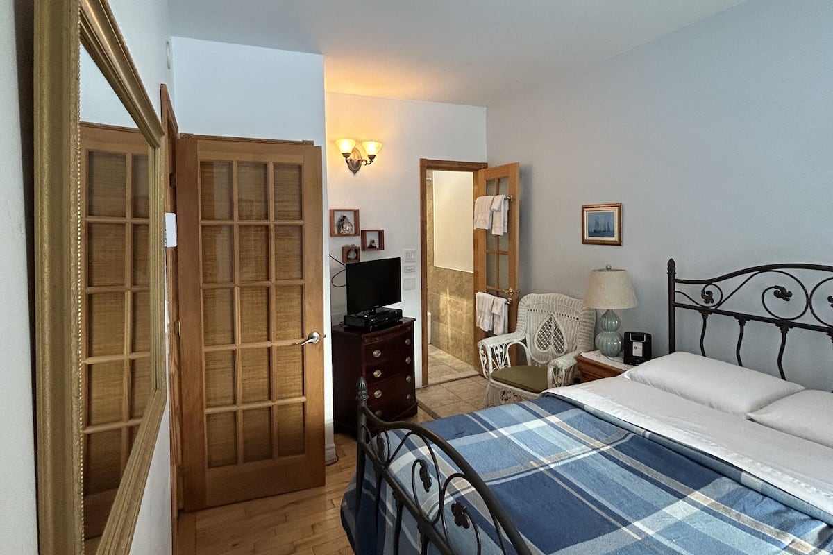 Une chambre à coucher avec un lit, une armoire en bois et un téléviseur posé sur une commode.
