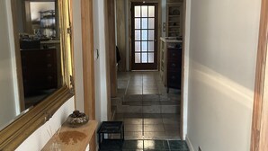A hallway with a marble floor, a wooden bench, a mirror, and a door leading to another room. - Le Sieur de Joliette (Montreal)