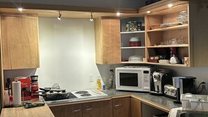 A compact kitchen with wooden cabinets, a microwave, a coffee maker, and a sink. - Le Sieur de Joliette (Montreal)