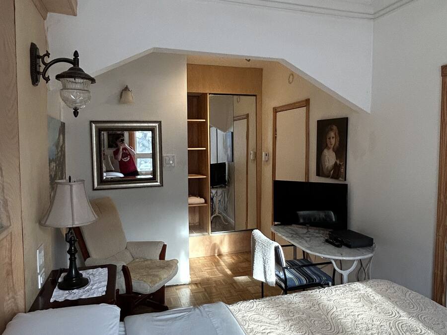 Ein Hotelzimmer mit zwei Betten, einem Deckenventilator, einem Schreibtisch mit Stuhl, einer Lampe, einem Spiegel und einem Kleiderschrank.