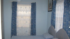 Un dormitorio con cama, cortinas y un cuadro en la pared.