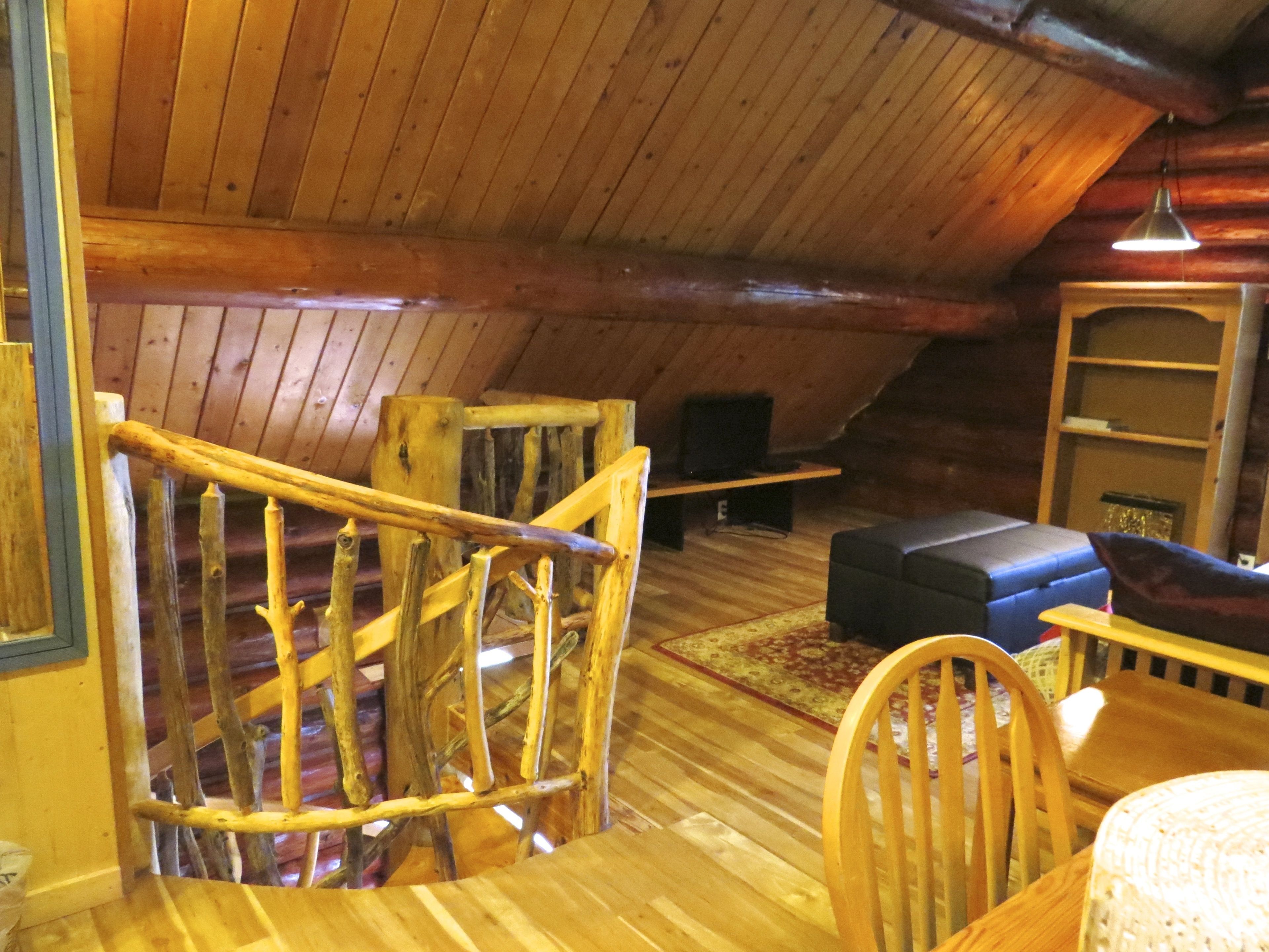A wooden interior with a staircase, a sofa, and a television.