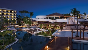 A resort with a swimming pool, wooden deck, and a building with multiple balconies. - Secrets Akumal Riviera Maya - Adults Only - All Inclusive (Akumal)