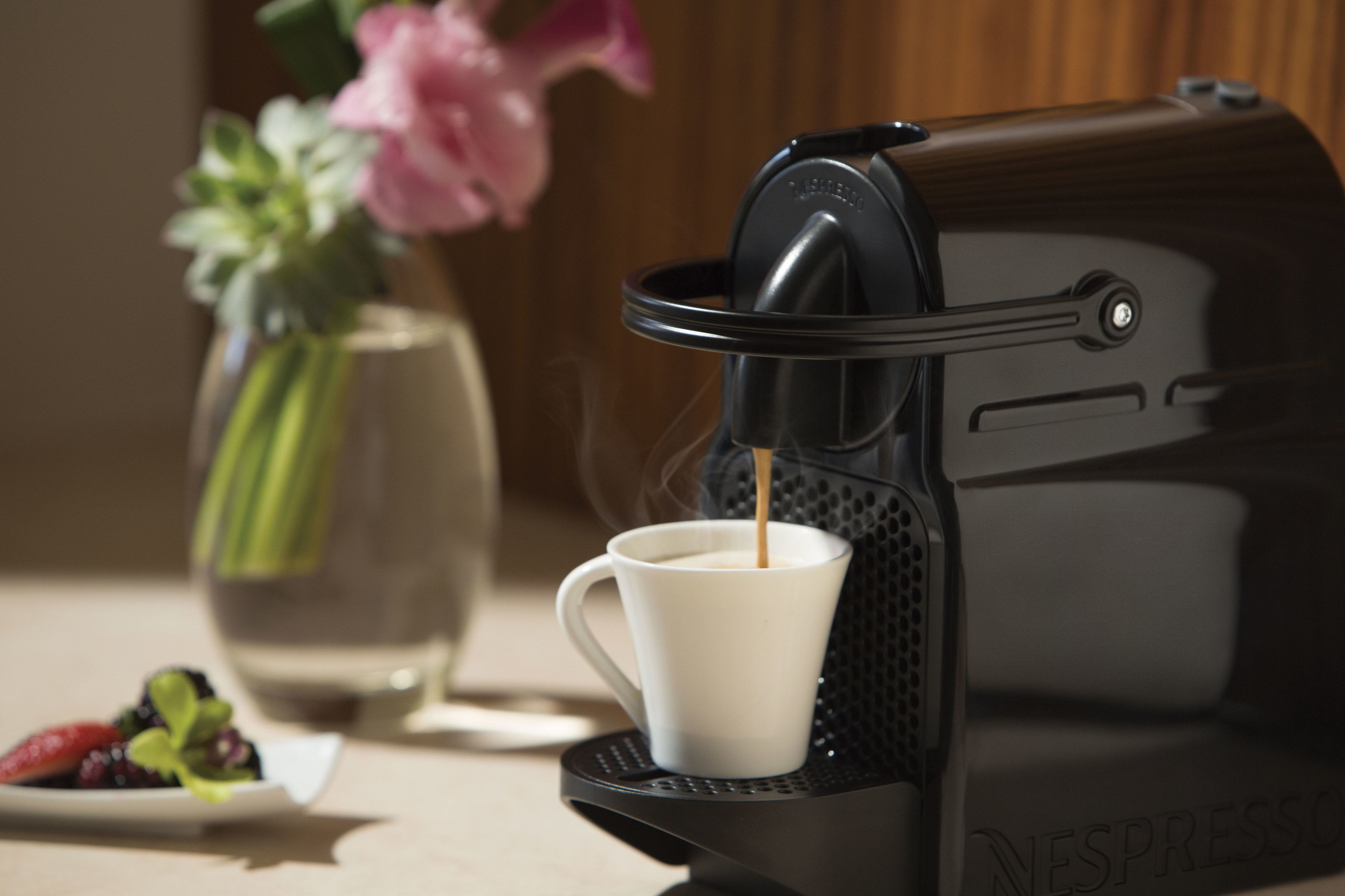 Een Nespresso koffieapparaat met een kop koffie die eruit komt.