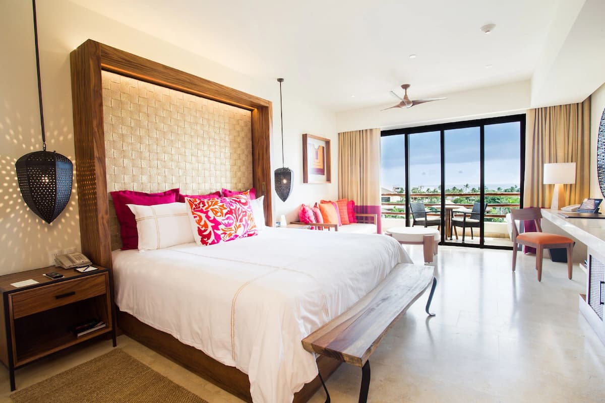 Um quarto espaçoso com uma cama grande, uma escrivaninha e uma varanda com vista.
