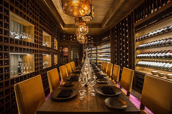 A long dining table set for a meal in a room with wine racks on both sides. - Secrets Akumal Riviera Maya - Adults Only - All Inclusive (Akumal)