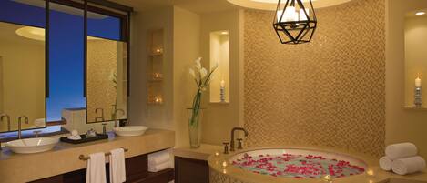 A modern bathroom with a large bathtub, two sinks, and a mirror.