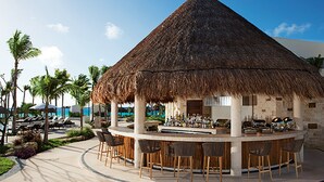 A thatched-roof bar area with bar stools, a poolside setting, and palm trees. - Secrets Akumal Riviera Maya - Adults Only - All Inclusive (Akumal)