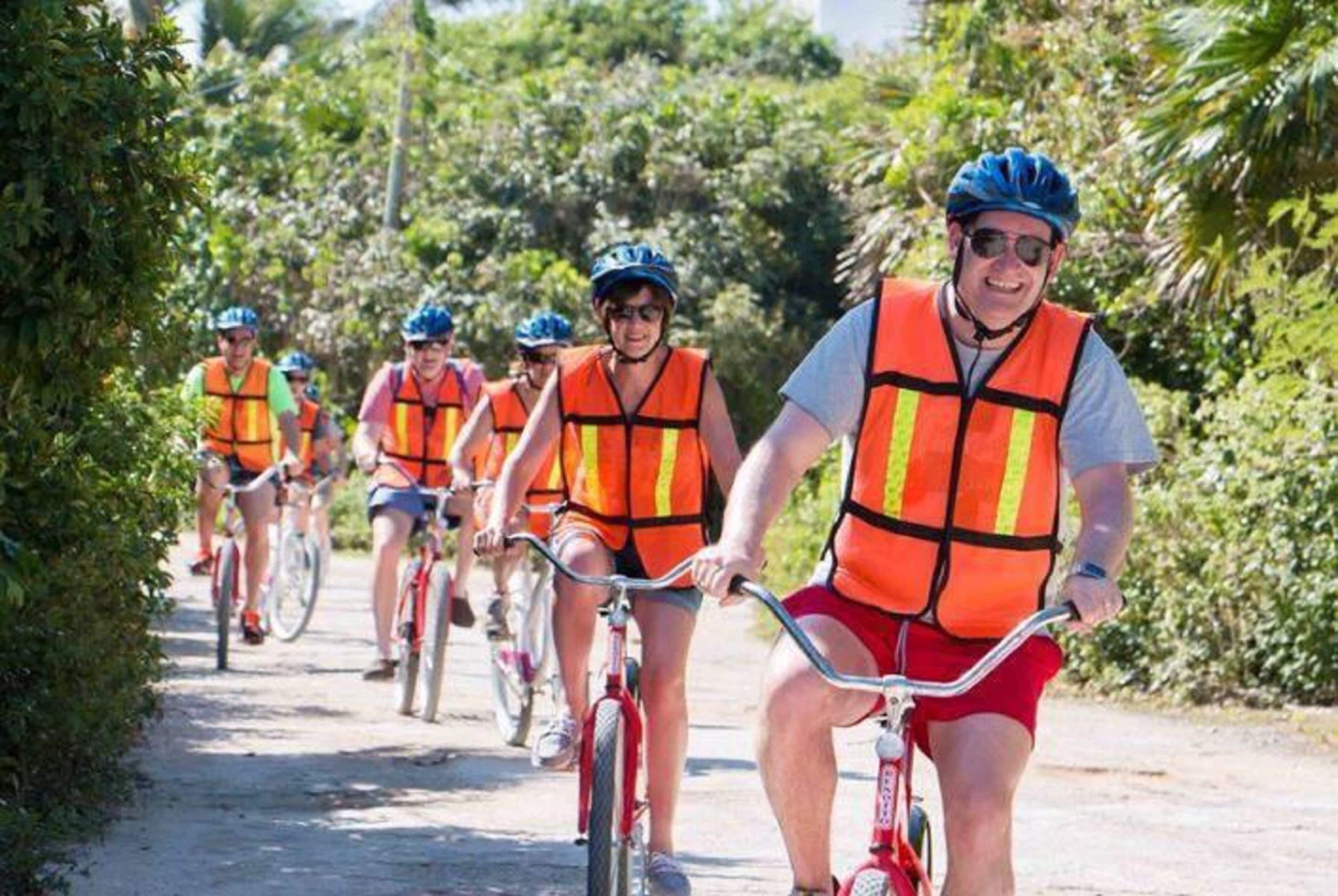 A group of cyclists on a paved path surrounded by greenery.