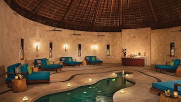 A spa area with a central pool, seating areas, and a reception desk.