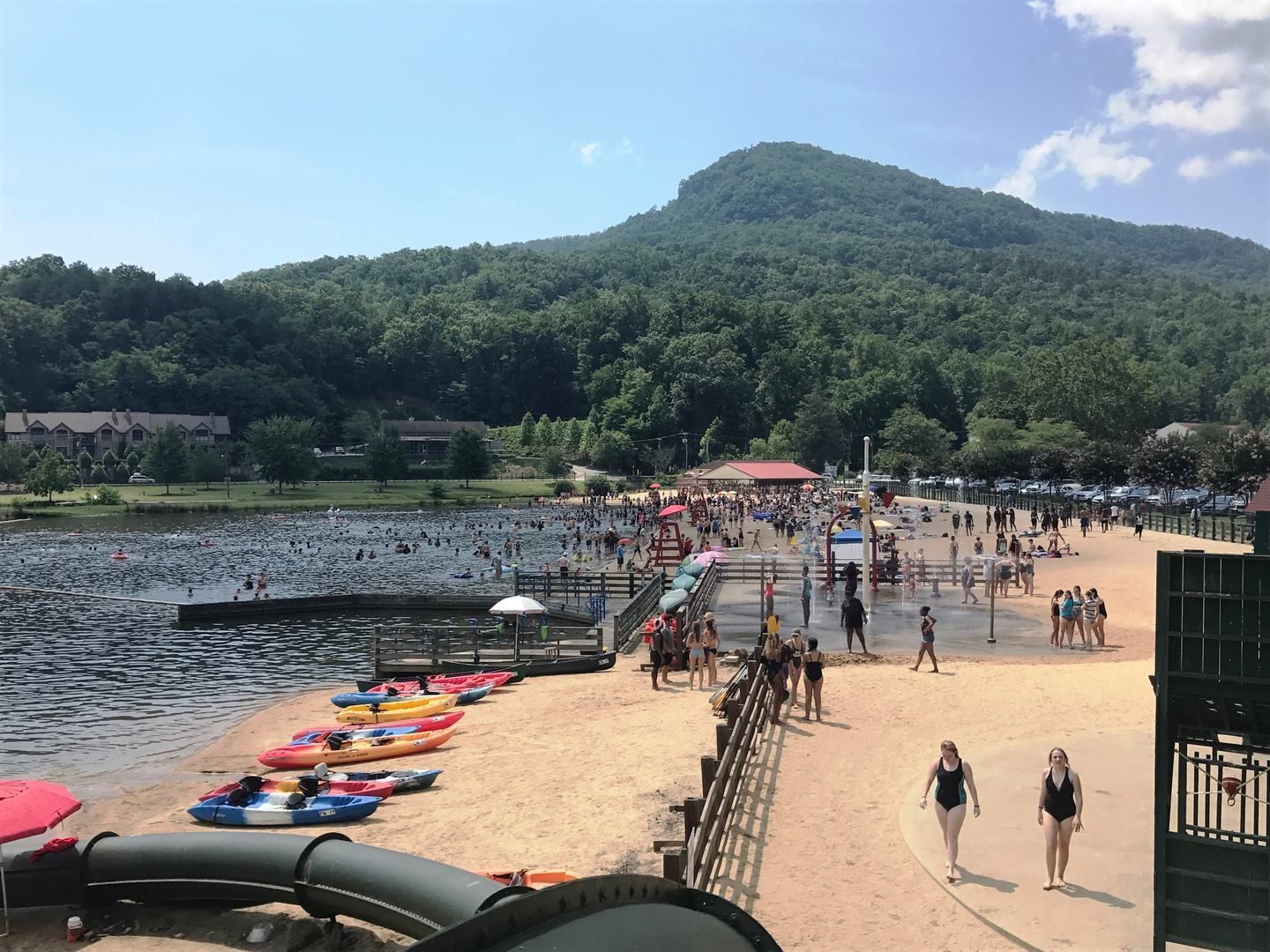 A lakeside beach with kayaks and a sandy walkway.