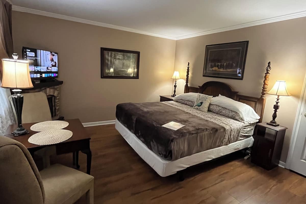 A hotel room with a bed, a television, a desk, and two lamps.
