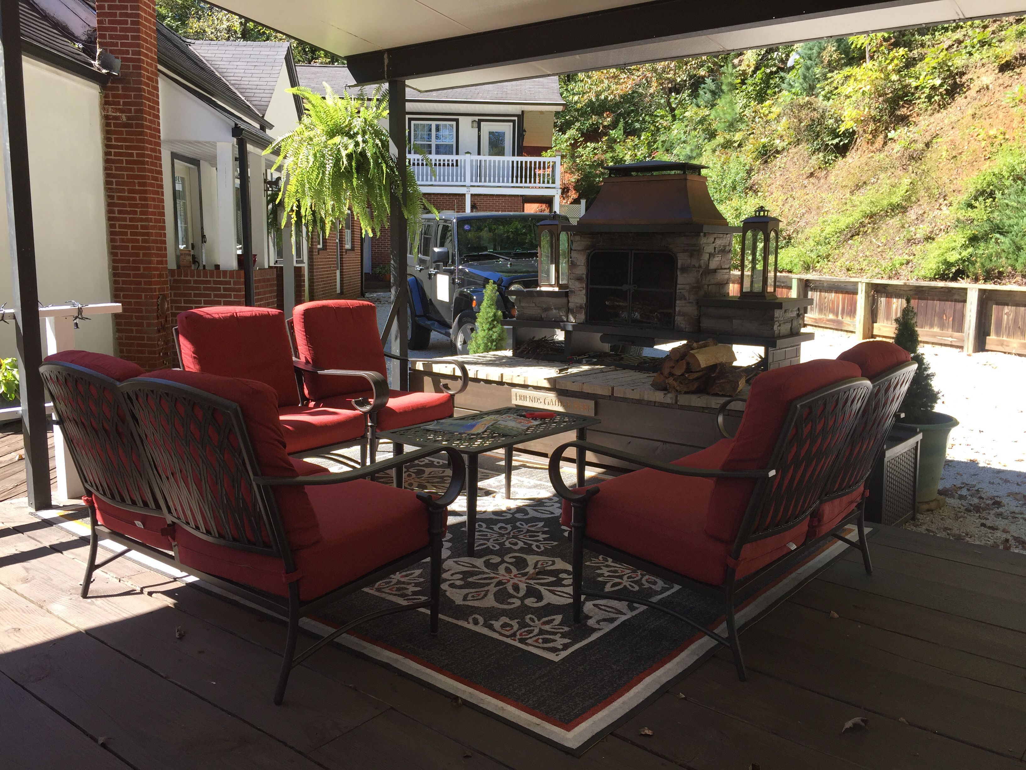 Eine Terrasse im Freien mit roten Stühlen, einem Tisch und einem Steinkamin.