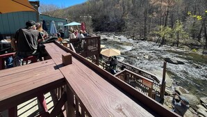 A wooden deck overlooking a river with a mountainous backdrop. - Grafton Lodge (Lake Lure)