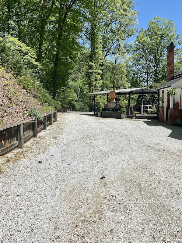 A covered outdoor area with a stone fireplace, a wooden deck, and a brick building. - Grafton Lodge (Lake Lure)