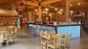 A restaurant interior with wooden beams, a bar area, and tables and chairs. - Grafton Lodge (Lake Lure)