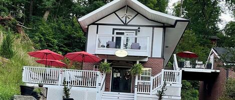 A two-story building with a balcony, red umbrellas, and a sign that reads 'Drive Through Slowly'.