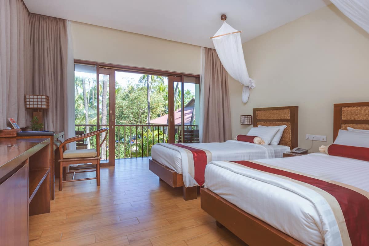 Une chambre d’hôtel avec deux lits, un bureau et une chaise.