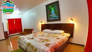 A hotel room with a bed, a painting of a waterfall, and a red curtain.