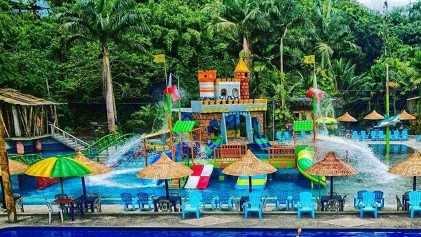 A swimming pool with a water slide and a play area.