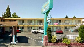 Een motel met een twee verdiepingen tellend gebouw, een overdekte ingang en een parkeerplaats met verschillende auto's.