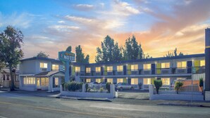 Een motel met meerdere kamers, een parkeerplaats en een bord met de naam van het motel.