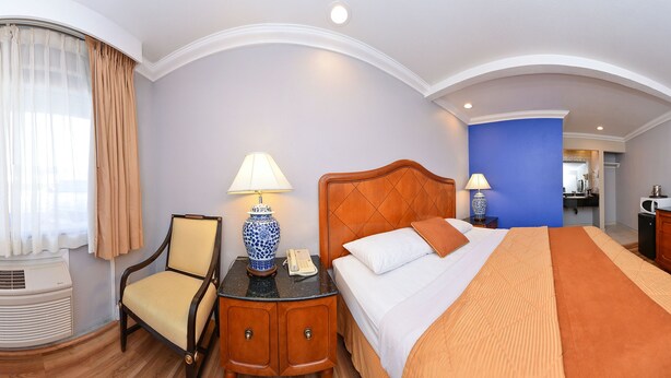 Een hotelkamer met een bed, nachtkastjes, een televisie en een badkamer die door een open deur zichtbaar is.