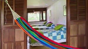 A room with two beds, a hammock, wooden walls, and a window with a view of greenery. - Cinaruco Caney (Villavicencio)