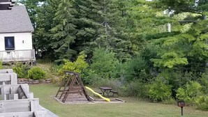 Een achtertuin met een houten speelconstructie, een picknicktafel en een brievenbus.