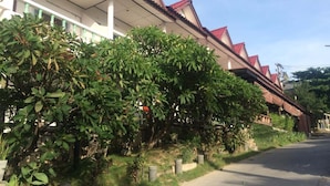 A residential building with a red roof and white walls, surrounded by lush greenery. - Baan Talay Guesthouse & Dormitory (Ko Pha-ngan)