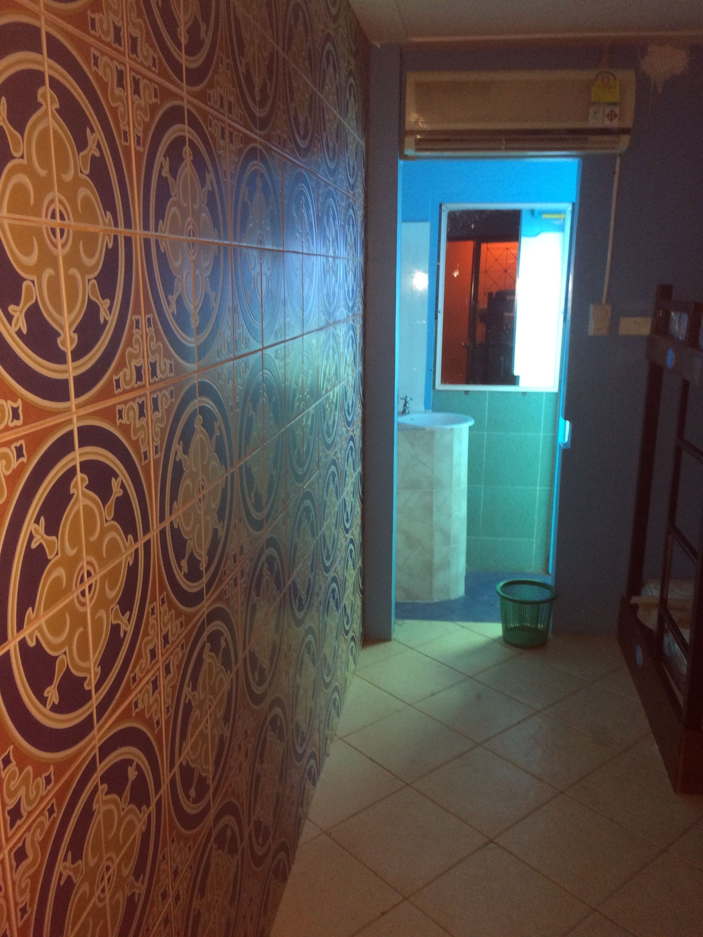 A bathroom with patterned tiles, a sink, and a window with a view of the outside.
