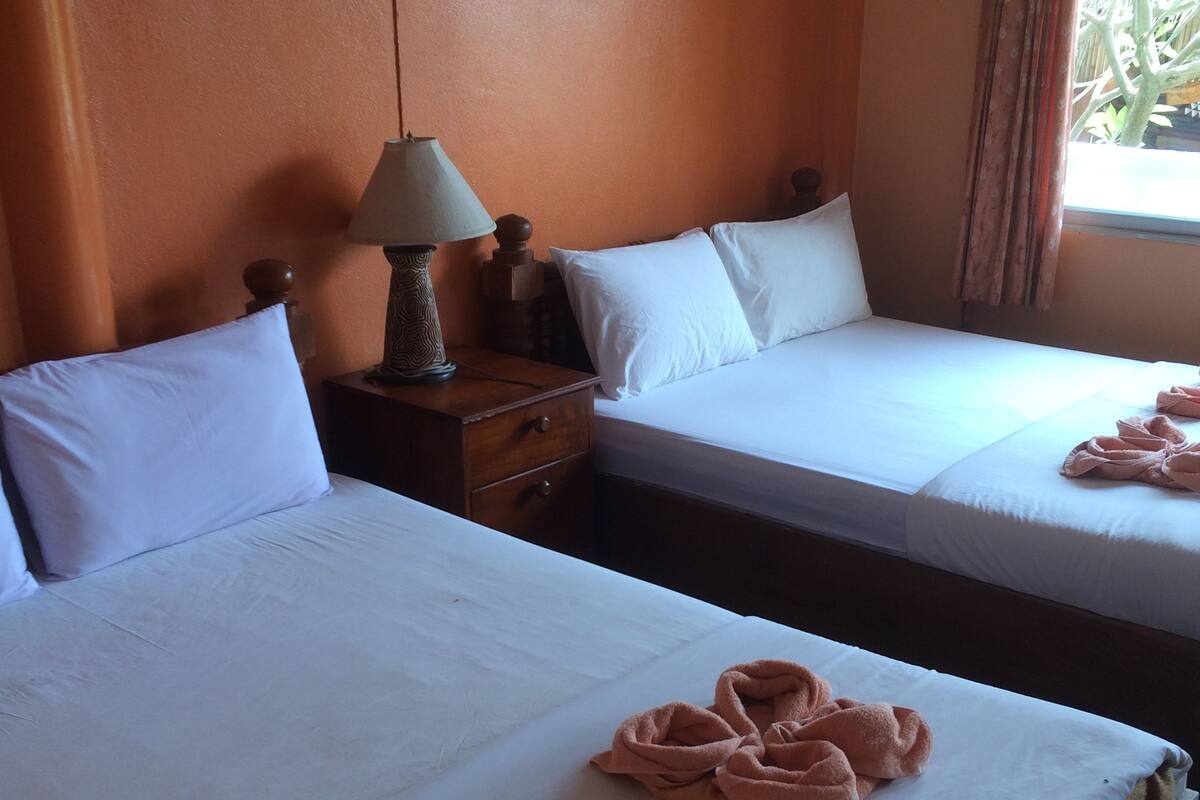 A hotel room with two beds, white linens, and towels arranged on the beds.