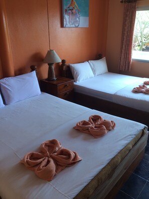 Ein Hotelzimmer mit zwei Betten, weißen Leintüchern und auf den Betten drapierten Handtüchern.