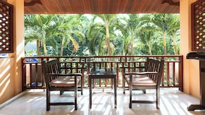 A wooden deck with two tables and chairs, overlooking a tropical garden with palm trees. - Asia Divers Resort (Koh Tao)