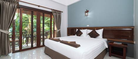 A large bed with a wooden headboard, a nightstand, and a window with curtains.