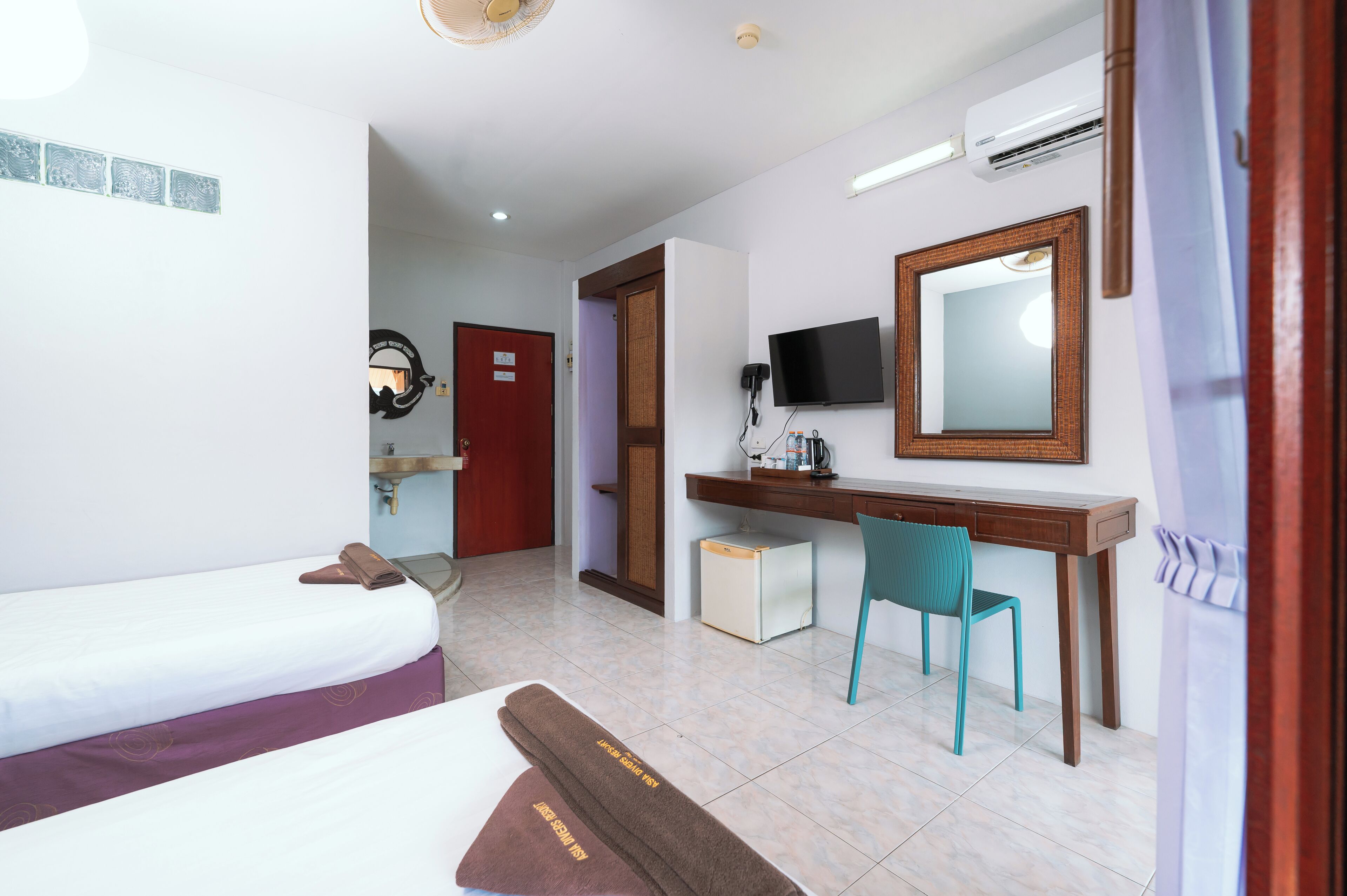Een hotelkamer met twee bedden, een bureau, een stoel, een televisie en een spiegel.