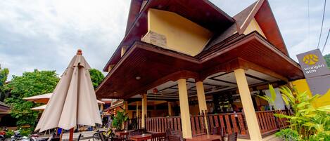 A wooden deck with outdoor seating and umbrellas, a sign for Asia Divers Resort, and a clear sky.