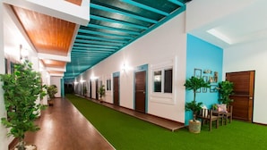 A hotel corridor with artificial grass, wooden flooring, and teal-colored ceiling beams. - Aukotan Place Hotel (Koh Tao)